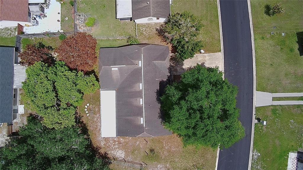 An aerial view shows a house with a dark roof surrounded by trees and grass — 136 PUELBA LANE, KISSIMMEE, FL