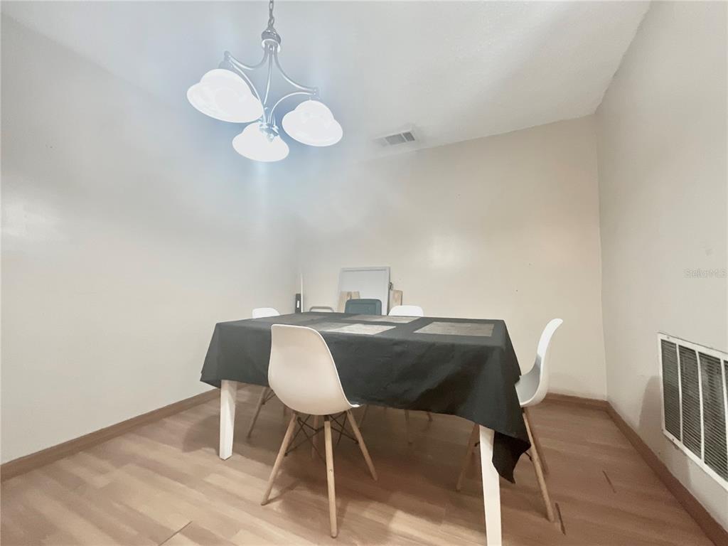 A dining room features a black tablecloth, four white chairs, and a three-light chandelier — 136 PUELBA LANE, KISSIMMEE, FL