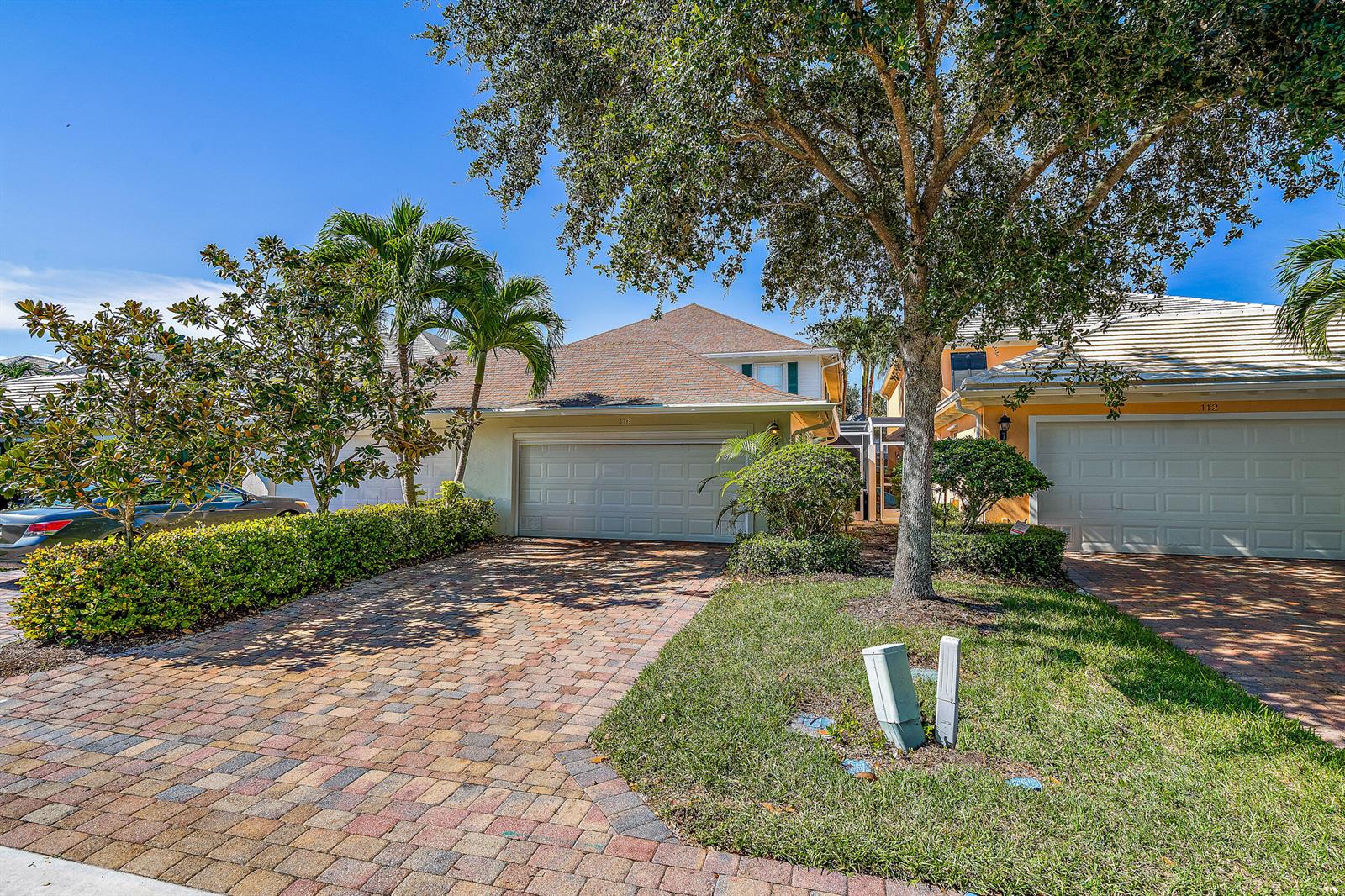 A two-story residential building features a paved driveway, a two-car garage, and mature landscaping — 116 Caravelle Drive, Jupiter FL 33458, JUPITER, FL