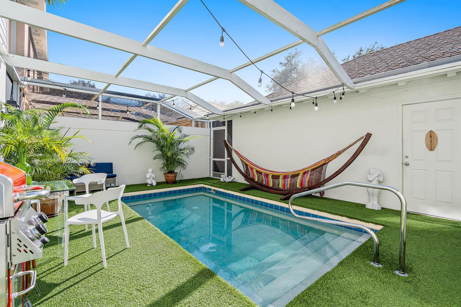 A small indoor swimming pool with a hammock and artificial turf under a screened enclosure — 116 Caravelle Drive, Jupiter FL 33458, JUPITER, FL
