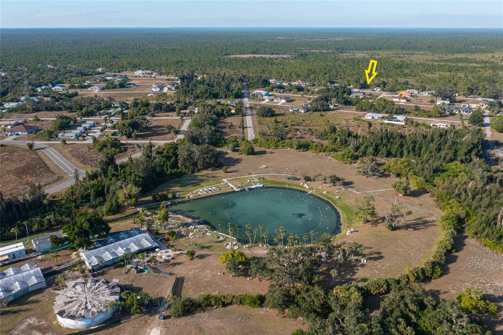 An aerial view shows a circular swimming pond surrounded by trees and residential houses — LOTS 17 & 18 HERNANDO ROAD, NORTH PORT, FL