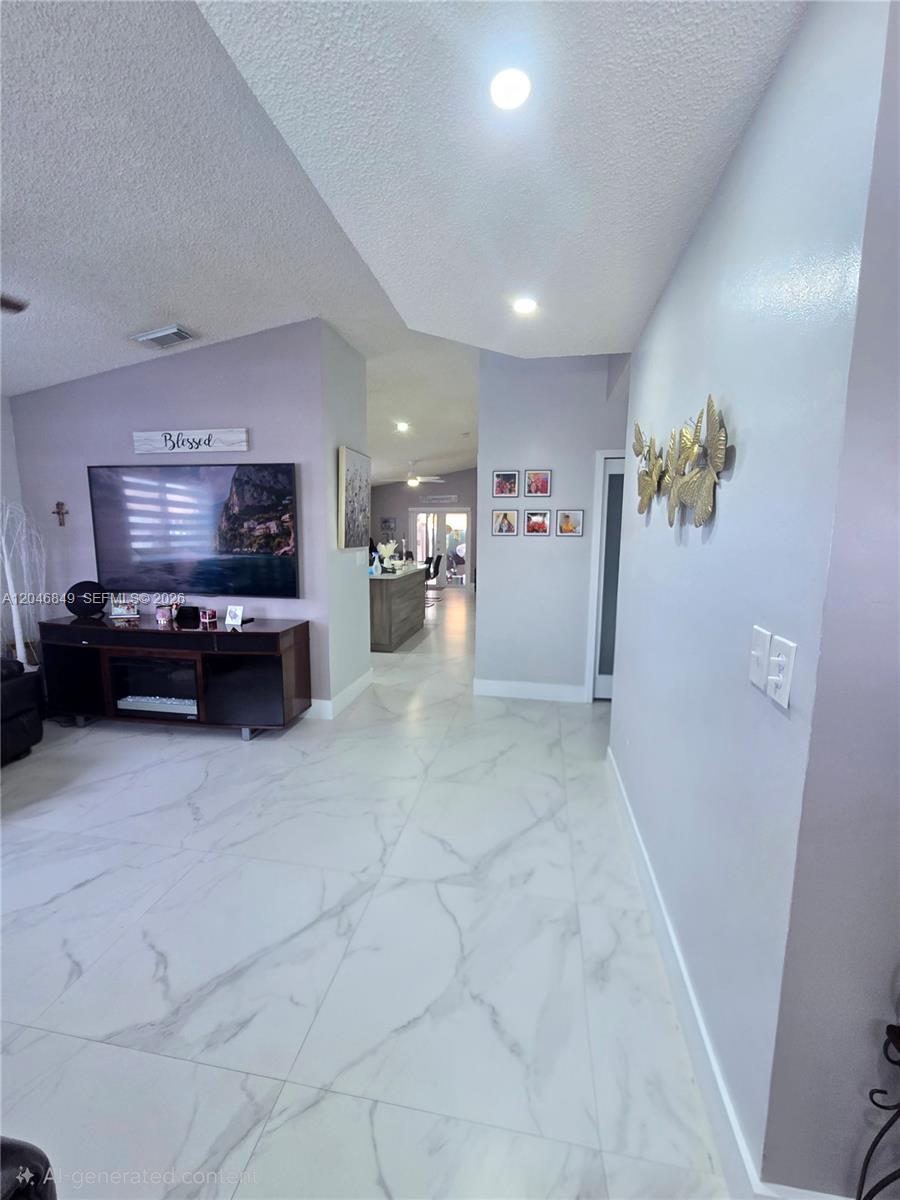 A living room with white marble-look tile flooring leads into a kitchen area — 2727 W 70th St, Hialeah FL 33016, HIALEAH, FL