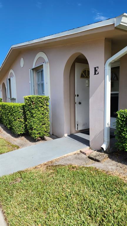 The exterior of a light-colored building features an arched entryway labeled with the letter E — 2784 DUDLEY DRIVE E UNIT E, WEST PALM BEACH, FL