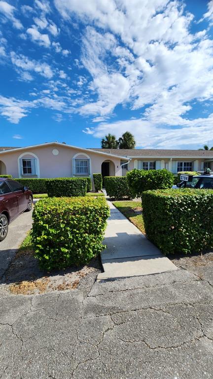 A single-story residential building with light-colored stucco walls and manicured hedges along the walkway — 2784 DUDLEY DRIVE E UNIT E, WEST PALM BEACH, FL