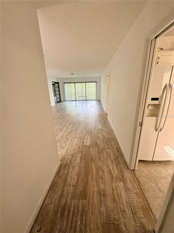 A view from a hallway looking into a living area with wood-look tile flooring — 7880 PALM AIRE LANE UNIT 203, SARASOTA, FL