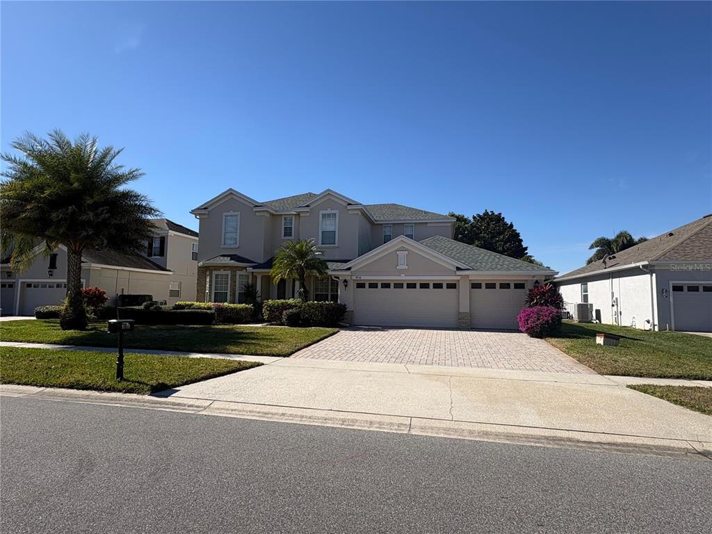 A two-story suburban house features a paved driveway, a three-car garage, and a palm tree — 9718 PINEOLA DRIVE, ORLANDO, FL