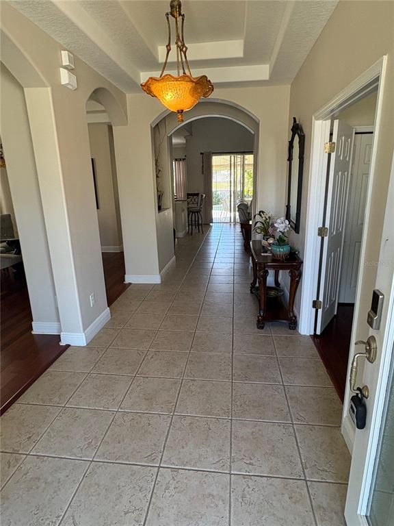 A tiled entryway leads to an arched hallway with a decorative pendant light fixture — 9718 PINEOLA DRIVE, ORLANDO, FL