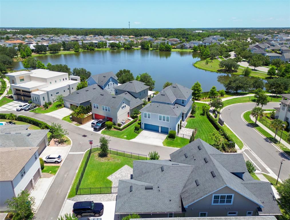 An aerial view shows suburban houses with gray roofs situated near a large lake — 13347 GABOR AVENUE, ORLANDO, FL