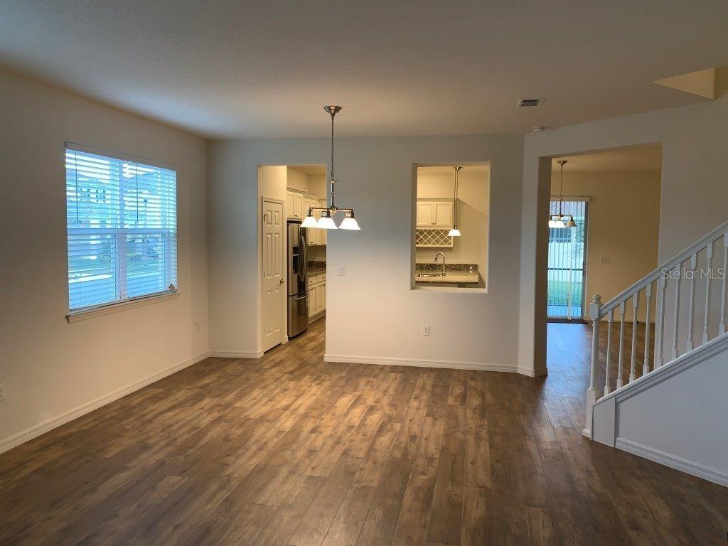 A dining area with wood-look flooring, a pendant light, and views into the kitchen — 3013 CHERRY ORCHARD LANE, WINTER GARDEN, FL