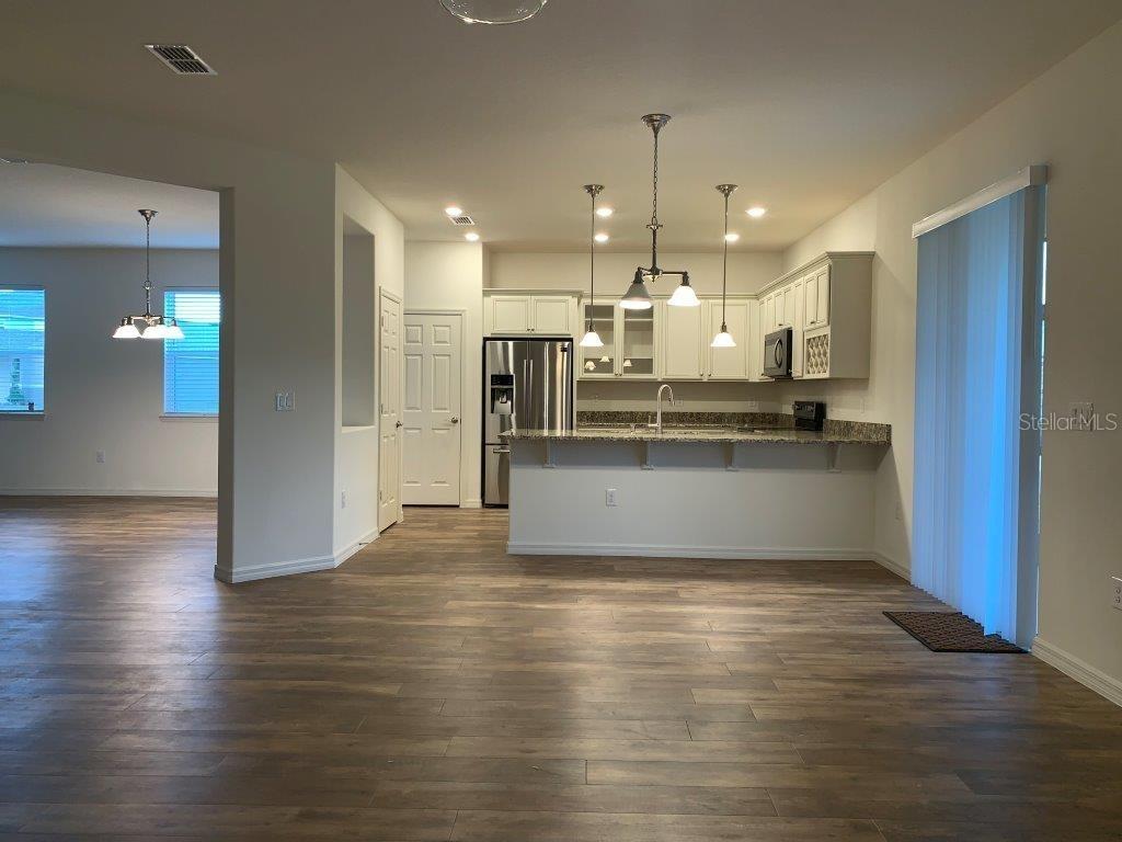 A kitchen with white cabinets, stainless steel appliances, and a breakfast bar overlooks a living area — 3013 CHERRY ORCHARD LANE, WINTER GARDEN, FL