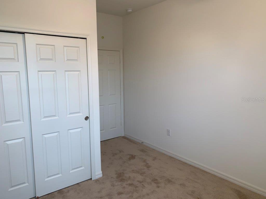 An empty room with beige carpet, white walls, and two sets of white closet doors — 3013 CHERRY ORCHARD LANE, WINTER GARDEN, FL