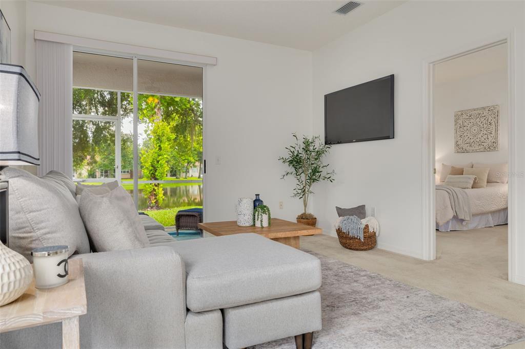 A living room with a gray sectional sofa, wooden coffee table, and sliding glass door — 3777 DARSTON STREET, PALM HARBOR, FL