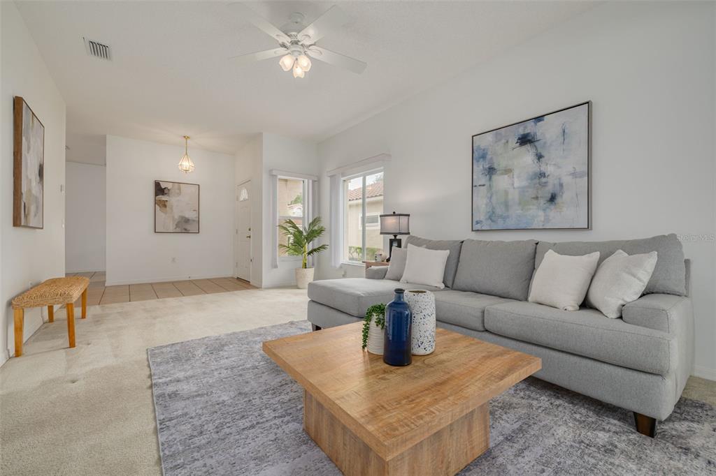 A living room features a grey sectional sofa, a wooden coffee table, and beige carpeting — 3777 DARSTON STREET, PALM HARBOR, FL