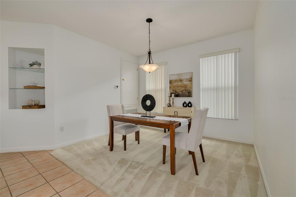A dining room features a wooden table, two chairs, a pendant light, and built-in shelving — 3777 DARSTON STREET, PALM HARBOR, FL