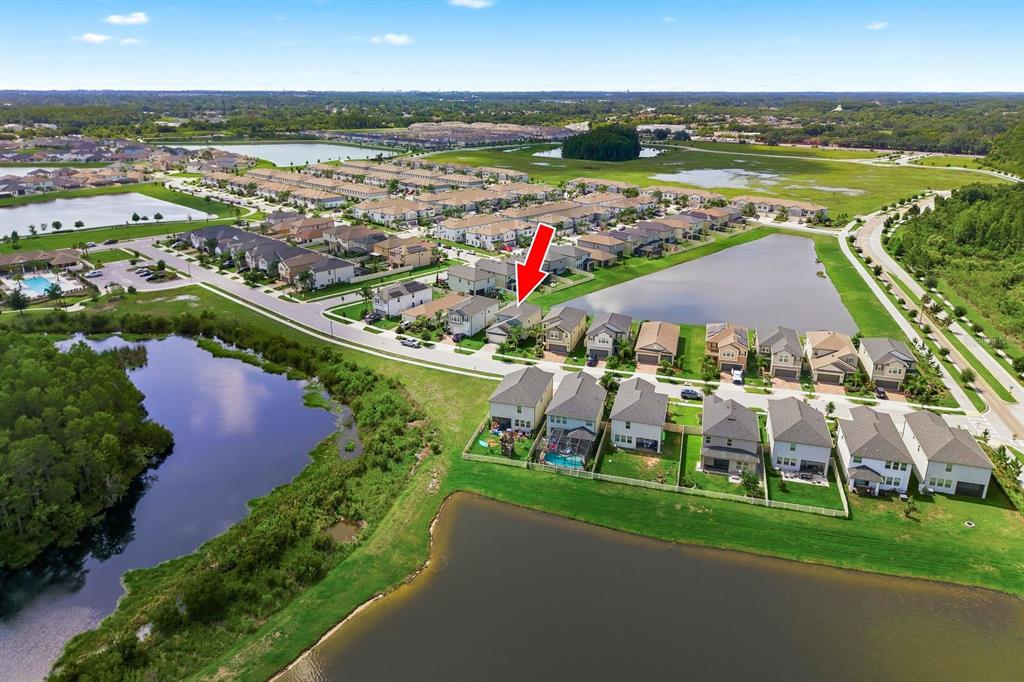 An aerial view shows a suburban neighborhood with houses surrounding several retention ponds — 8683 WINNING FIELDS ROAD, NEW PORT RICHEY, FL