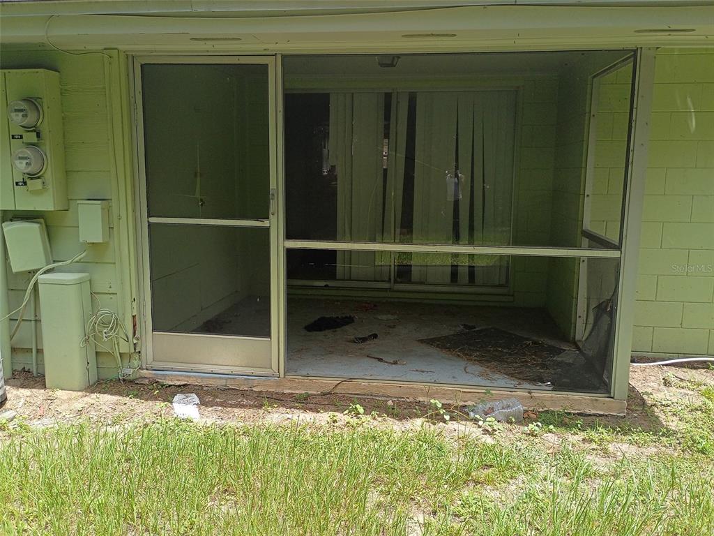 A screened-in porch with a sliding glass door and an adjacent electrical meter box — 7272 BALBOA DRIVE UNIT 7272, ORLANDO, FL