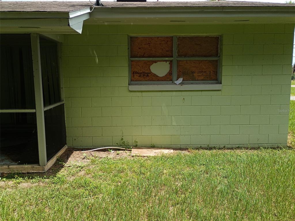 An exterior view of a light green concrete block wall with a boarded-up window — 7272 BALBOA DRIVE UNIT 7272, ORLANDO, FL