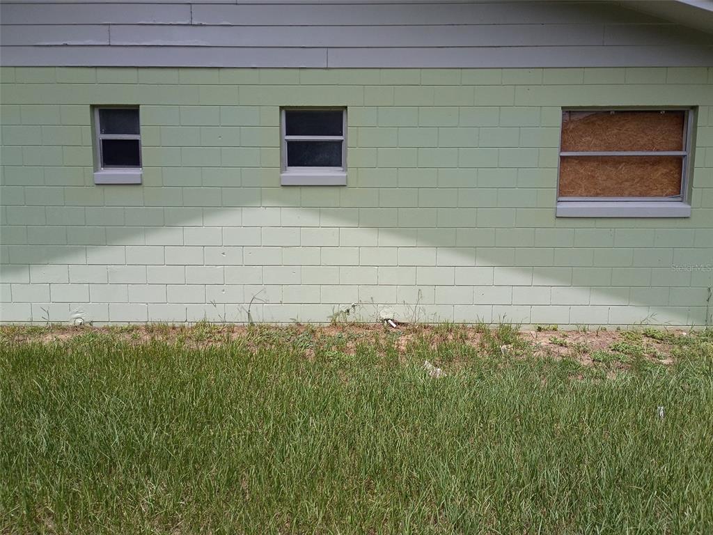 A light green concrete block exterior wall features three windows, one of which is boarded up — 7272 BALBOA DRIVE UNIT 7272, ORLANDO, FL