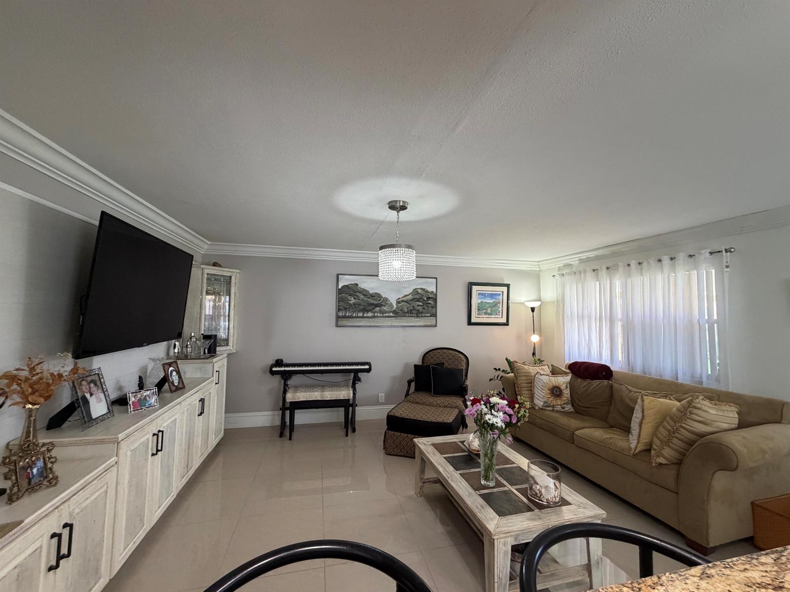A living room features a beige sofa, a coffee table, a piano, and a television — 292 Brittany G # 292, Delray Beach FL 33446, DELRAY BEACH, FL