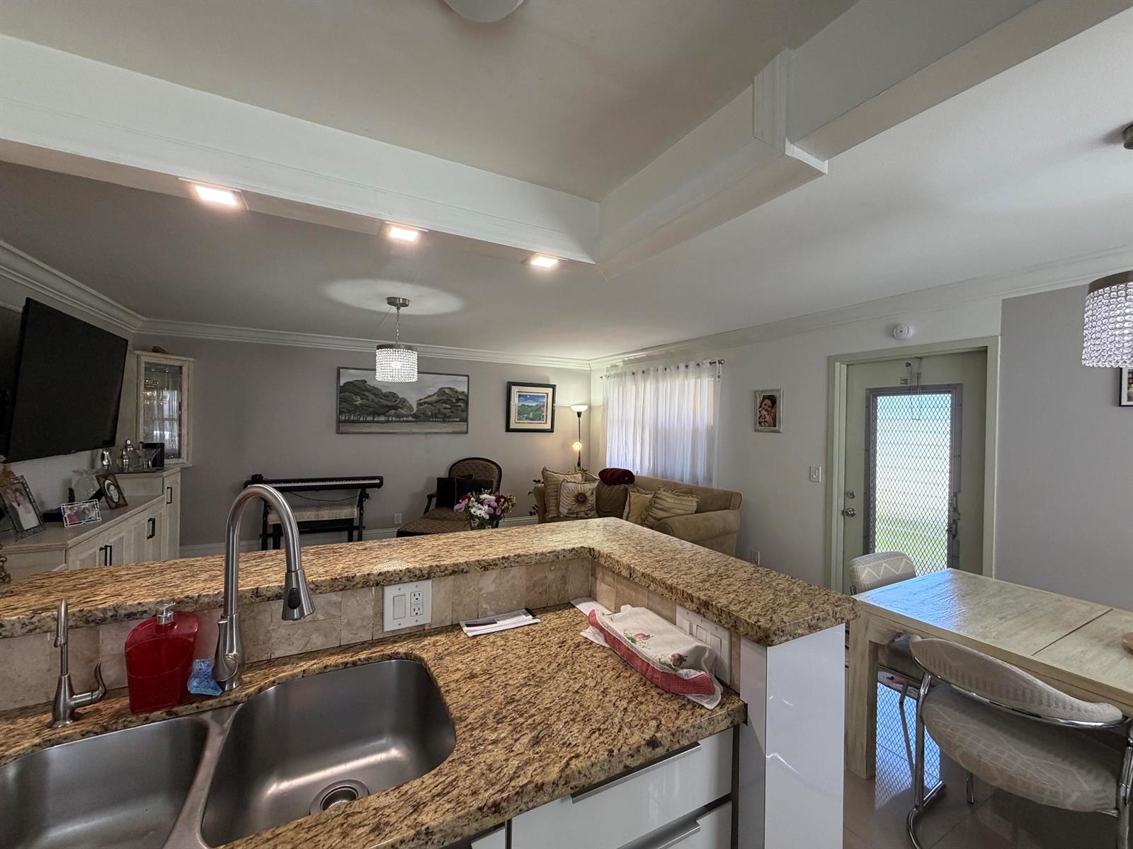 A kitchen with granite countertops overlooks a living room and a dining area — 292 Brittany G # 292, Delray Beach FL 33446, DELRAY BEACH, FL