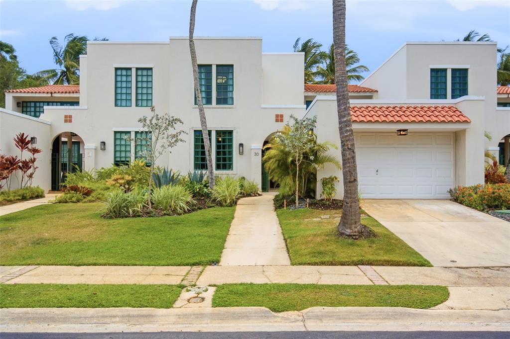 A two-story white stucco townhouse features a tiled roof, green-framed windows, and a front garage — 30 CALLE ARENAS, DORADO, PR