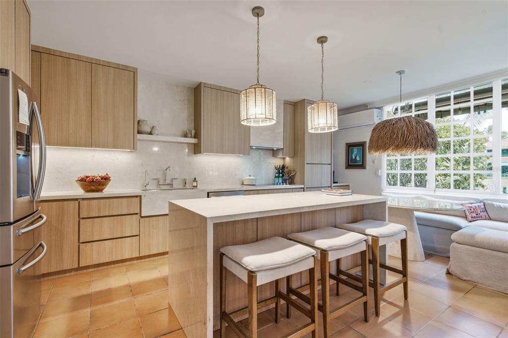 A kitchen with light wood cabinets, a stone island with three stools, and tile flooring — 30 CALLE ARENAS, DORADO, PR