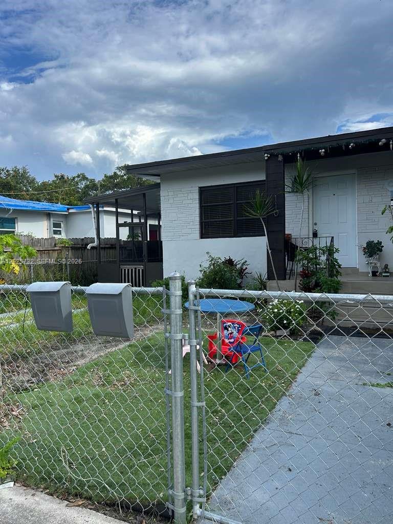 A front yard with a chain-link fence, a small table, and chairs before a house — 110 NW 58th St # 0, Miami FL 33127, MIAMI, FL