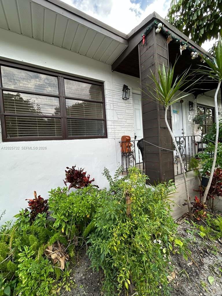 A white brick house exterior features a covered porch with dark wooden support columns — 110 NW 58th St # 0, Miami FL 33127, MIAMI, FL