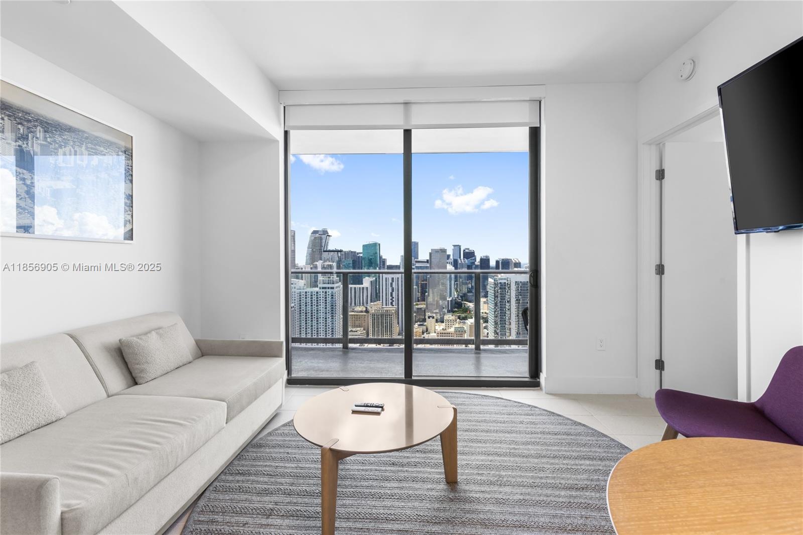 A living room features a sofa, round coffee table, purple chair, and a balcony view — 601 NE 1st Ave # 4607, Miami FL 33132, MIAMI, FL