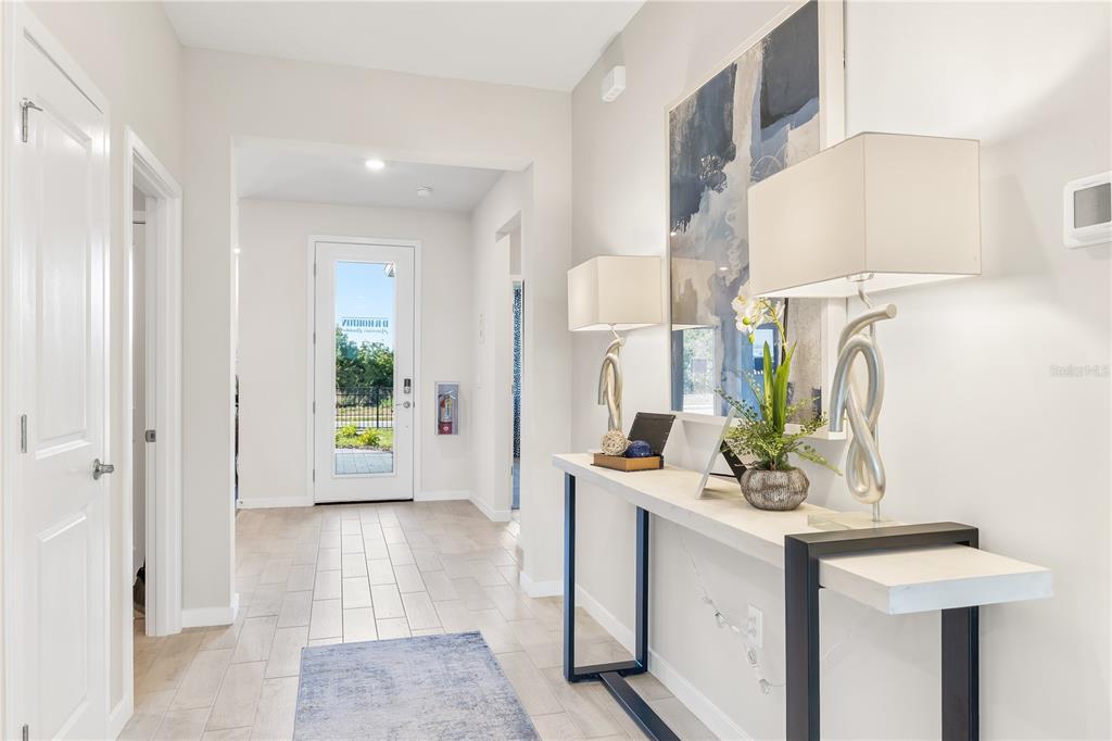 A bright entryway features light wood-look tile floors, a console table, and a glass-paneled door — 12775 SEAGRASS DRIVE, PUNTA GORDA, FL