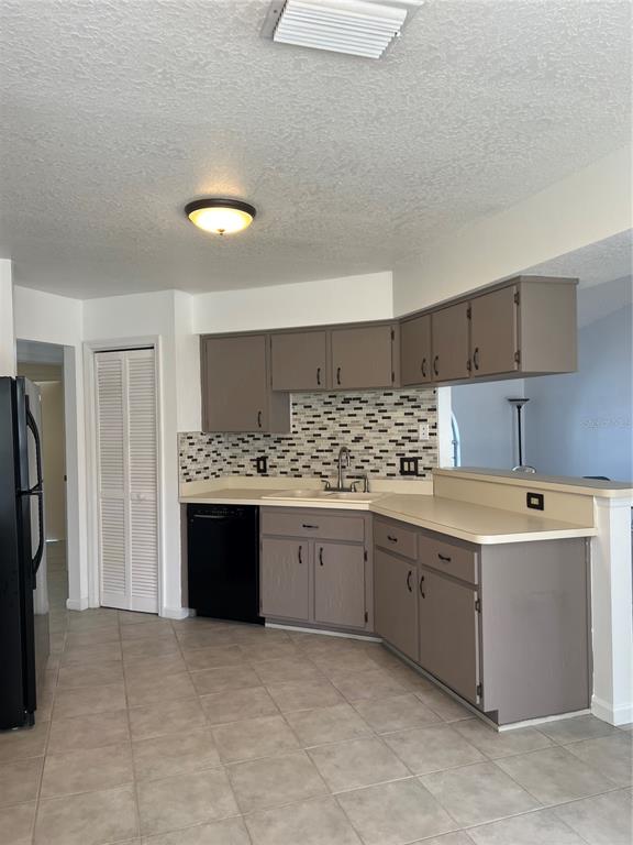 A kitchen features taupe cabinets, a mosaic tile backsplash, black appliances, and beige countertops — 5307 EL CERRO DRIVE, NEW PORT RICHEY, FL