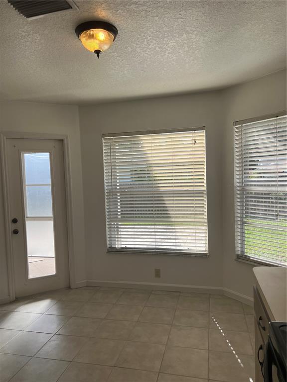A bright breakfast nook features tiled flooring, a glass-paneled door, and two windows with blinds — 5307 EL CERRO DRIVE, NEW PORT RICHEY, FL