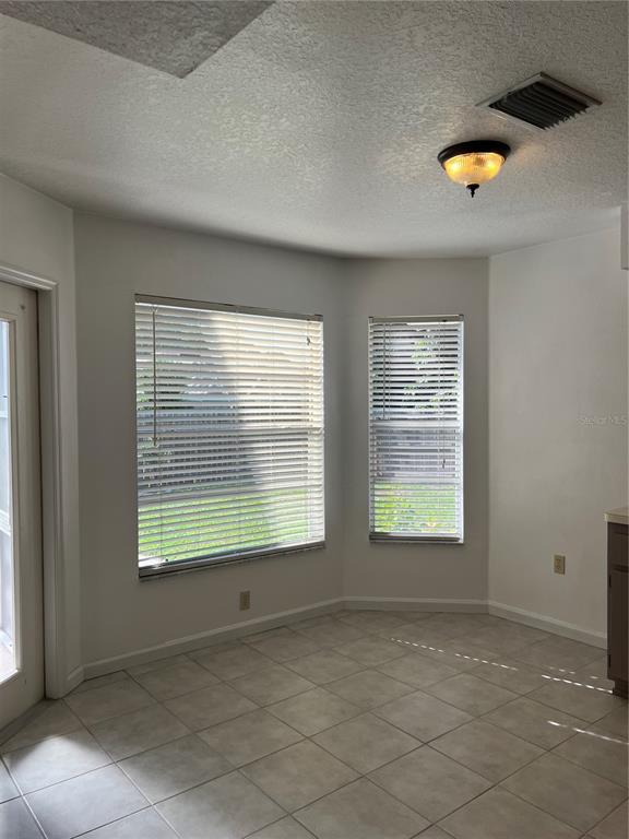 A bright breakfast nook features light tile flooring, white walls, and two windows with blinds — 5307 EL CERRO DRIVE, NEW PORT RICHEY, FL