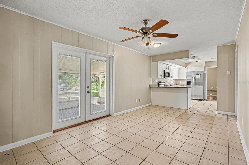 A tiled dining area features wood-paneled walls, a ceiling fan, and French doors to a porch — 1534 HALLAM COURT S, LAKELAND, FL