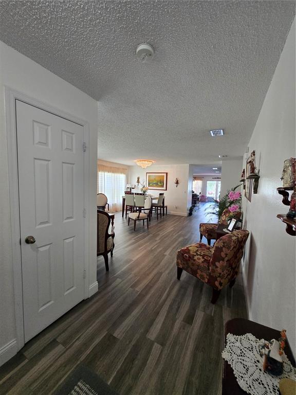A view from a hallway into a dining area with wood-look flooring and white walls — 3277 AMBERLEY PARK CIRCLE, KISSIMMEE, FL