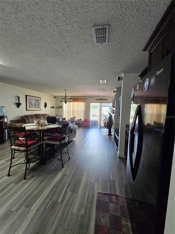 A dining area and living room feature wood-look flooring and a sliding glass door — 3277 AMBERLEY PARK CIRCLE, KISSIMMEE, FL