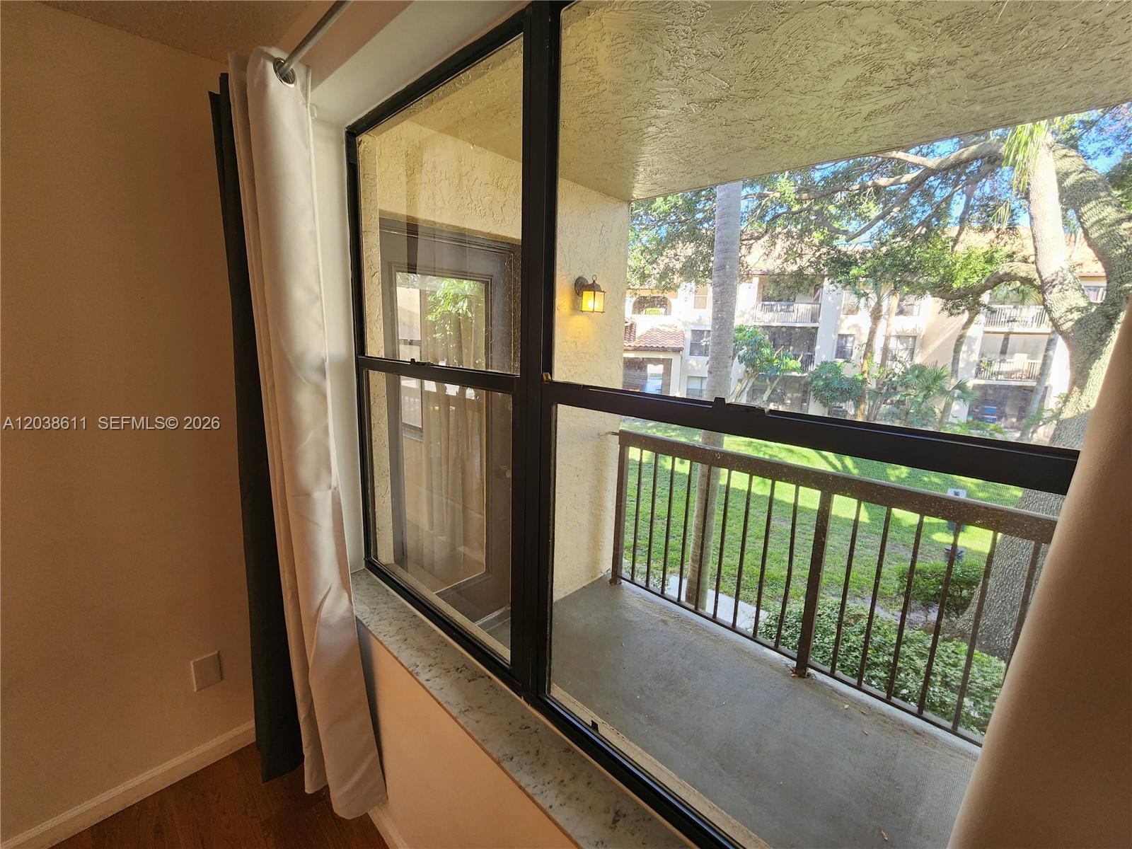 A view from a window looks out onto a balcony with a metal railing — 4401 W Mcnab Rd # 16, Pompano Beach FL 33069, POMPANO BEACH, FL