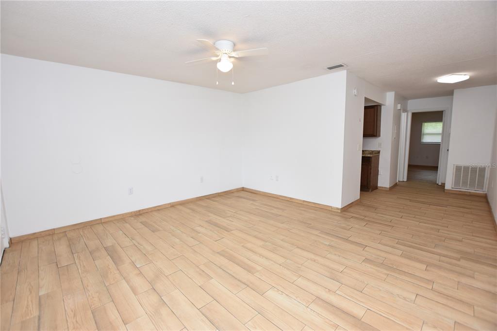 An empty room with light wood-look tile flooring, white walls, and a ceiling fan — 613 ROBIN ROAD UNIT 5, LAKELAND, FL