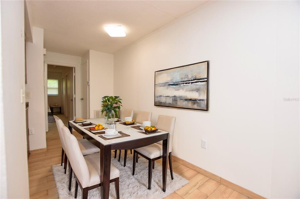 A dining room features a dark wood table, six chairs, and a large abstract painting — 613 ROBIN ROAD UNIT 5, LAKELAND, FL