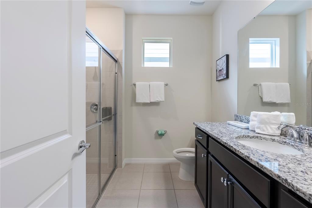 A bathroom features a glass-enclosed shower, a granite vanity, and a toilet — 4425 KAIPO ROAD, DAVENPORT, FL
