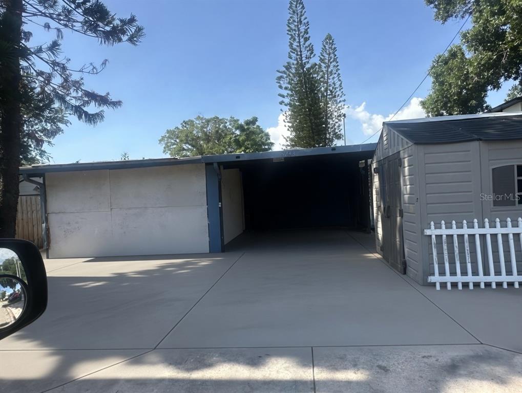 A concrete driveway leads to a covered carport next to a small storage shed — 5234 9TH AVENUE N, ST PETERSBURG, FL