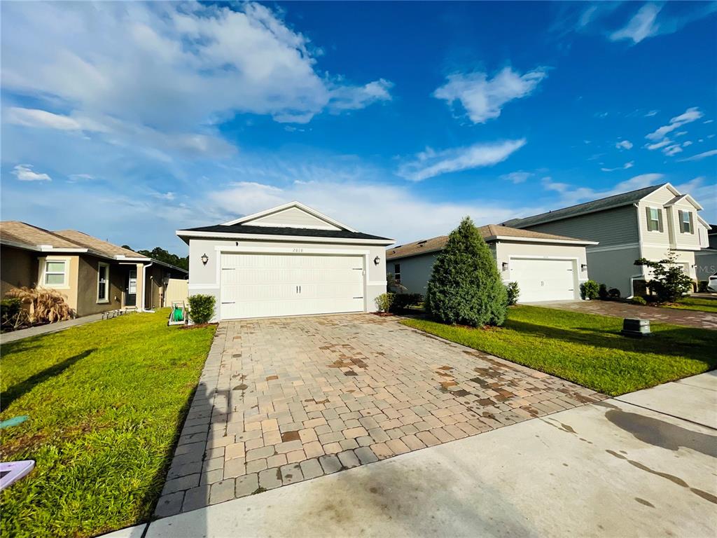 A suburban house with a white garage door and a paved driveway under a blue sky — 2818 SANCTUARY DRIVE, CLERMONT, FL