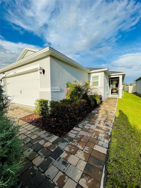 A side view of a house with a garage, paver walkway, and landscaped garden — 2818 SANCTUARY DRIVE, CLERMONT, FL