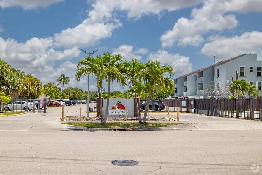 The exterior of the Los Sueños Condominium complex features a gated entrance with palm trees — 1725 W 60th St # F202, Hialeah FL 33012, HIALEAH, FL