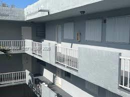An exterior view of a multi-story apartment building with white railings and gray walls — 1725 W 60th St # F202, Hialeah FL 33012, HIALEAH, FL