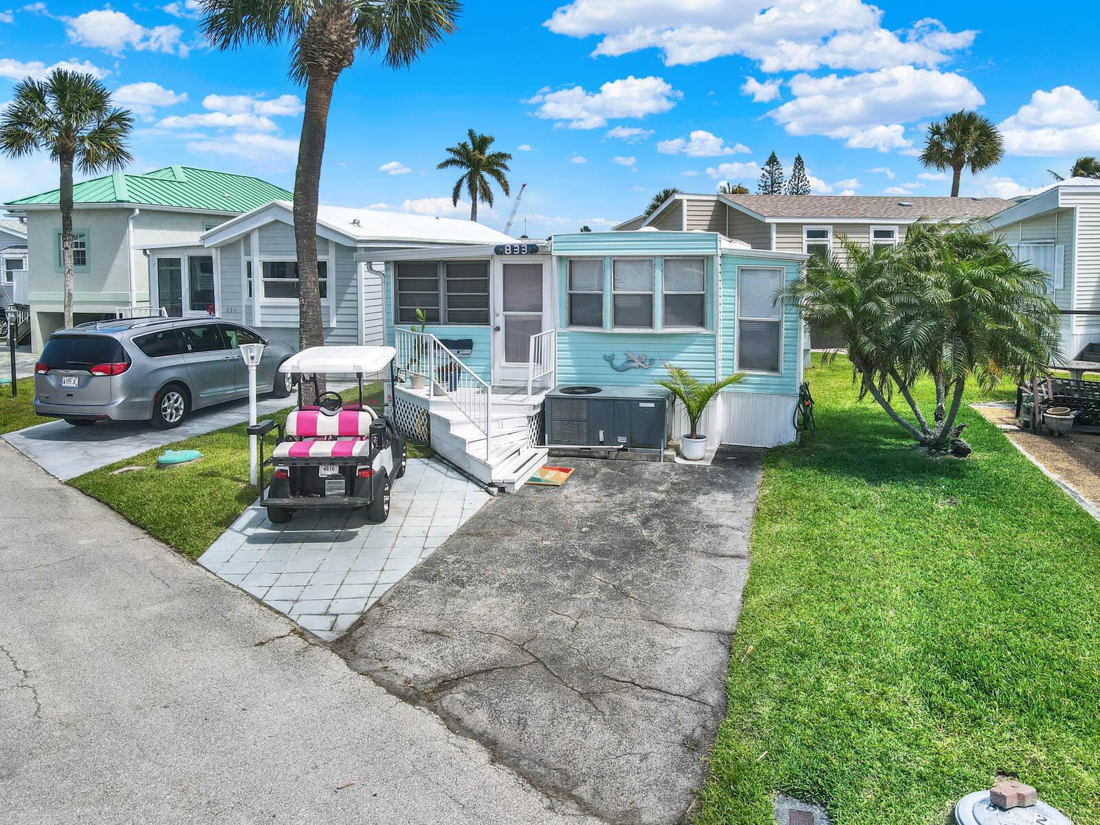 A light blue mobile home with a golf cart parked on a paved driveway — 833 Nettles Boulevard, Jensen Beach FL 34957, JENSEN BEACH, FL
