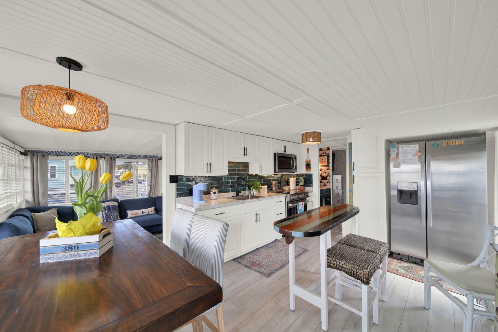 A kitchen and dining area features white cabinets, a dark backsplash, and a wooden table — 833 Nettles Boulevard, Jensen Beach FL 34957, JENSEN BEACH, FL