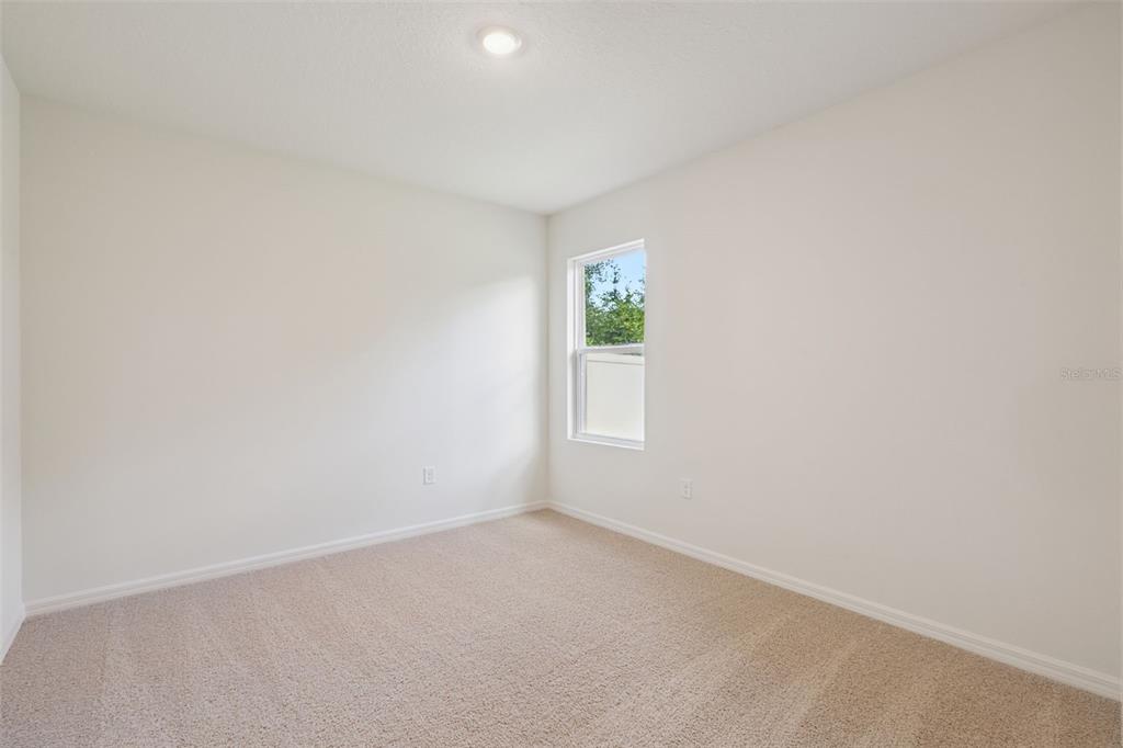 An empty bedroom features beige carpet, white walls, a single window, and a recessed ceiling light — 2516 DORSET COURT, ORMOND BEACH, FL