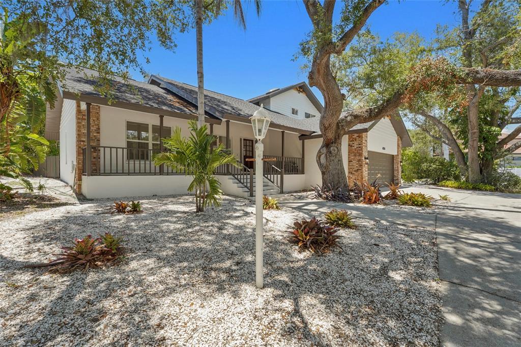 A single-story house with a white exterior, brick accents, a front porch, and gravel landscaping — 4074 REDBIRD CIRCLE, SARASOTA, FL