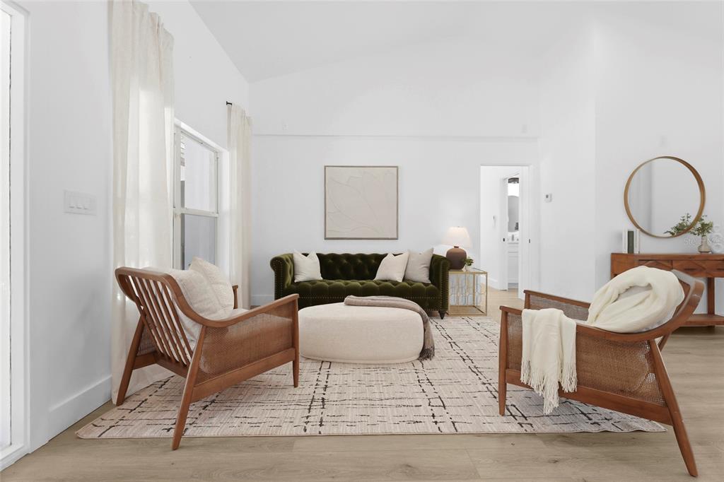 A living room features a green tufted sofa, two wooden armchairs, and a round ottoman — 4074 REDBIRD CIRCLE, SARASOTA, FL